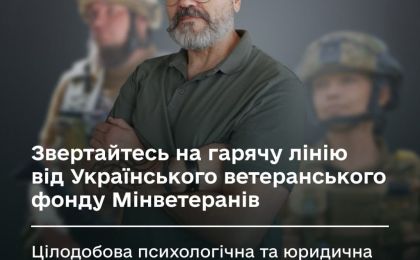 Чоловік із бородою та окулярами стоїть із схрещеними руками на передньому плані, на фоні — розмиті фігури військових у формі. Український текст на зображенні закликає звертатися на гарячу лінію Українського ветеранського фонду Мінветеранів, яка надає цілодобову психологічну та юридичну підтримку. Візуальне посилення теми турботи про ветеранів.